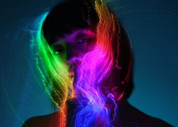 Rainbow light streaks illuminate a person's face.