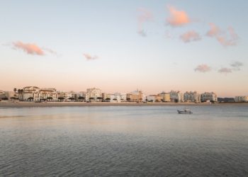 City skyline meets the sea under a calm sky.