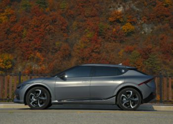 a silver car parked on the side of a road with trees in the background