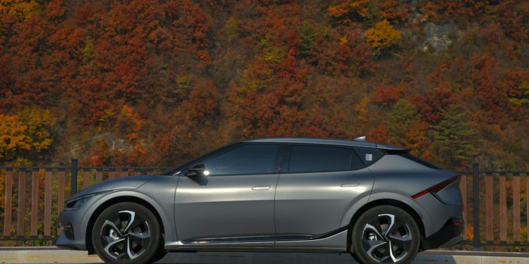 a silver car parked on the side of a road with trees in the background