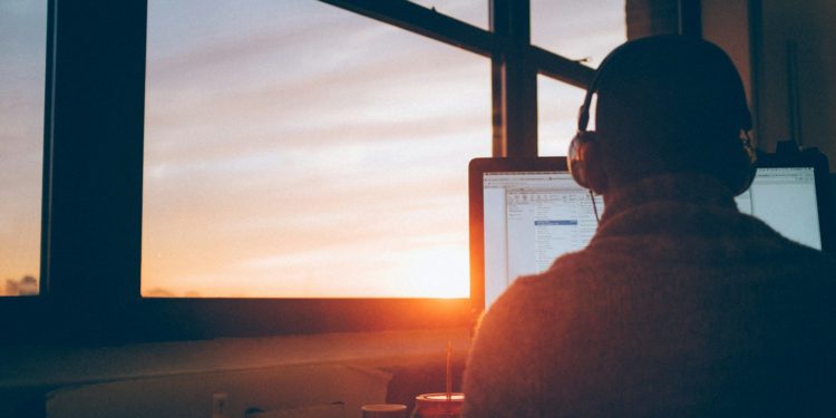 man sitting facing monitor