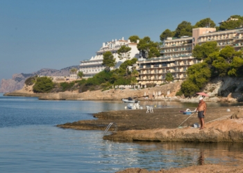 a man standing on a beach next to a body of water