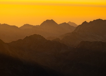 Mountains are silhouetted by a beautiful, golden sunset.