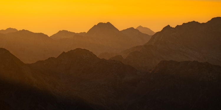 Mountains are silhouetted by a beautiful, golden sunset.