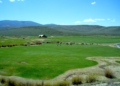 green grass field near mountain under blue sky during daytime