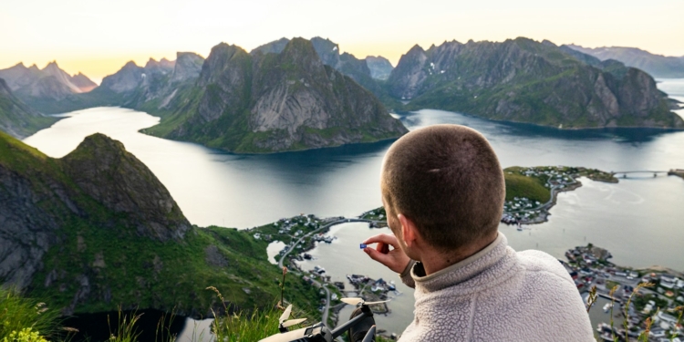Man painting a scenic norwegian fjord landscape from above