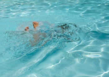 A man swimming in a pool with no shirt on