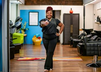 Woman in salon gives peace sign towards camera