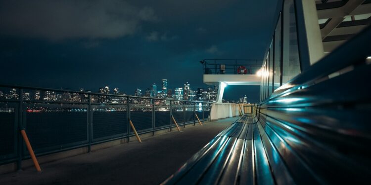 City skyline at night seen from a ferry deck.